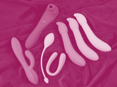 air pulse sex toy next to several types of dildos, on top of black blanket