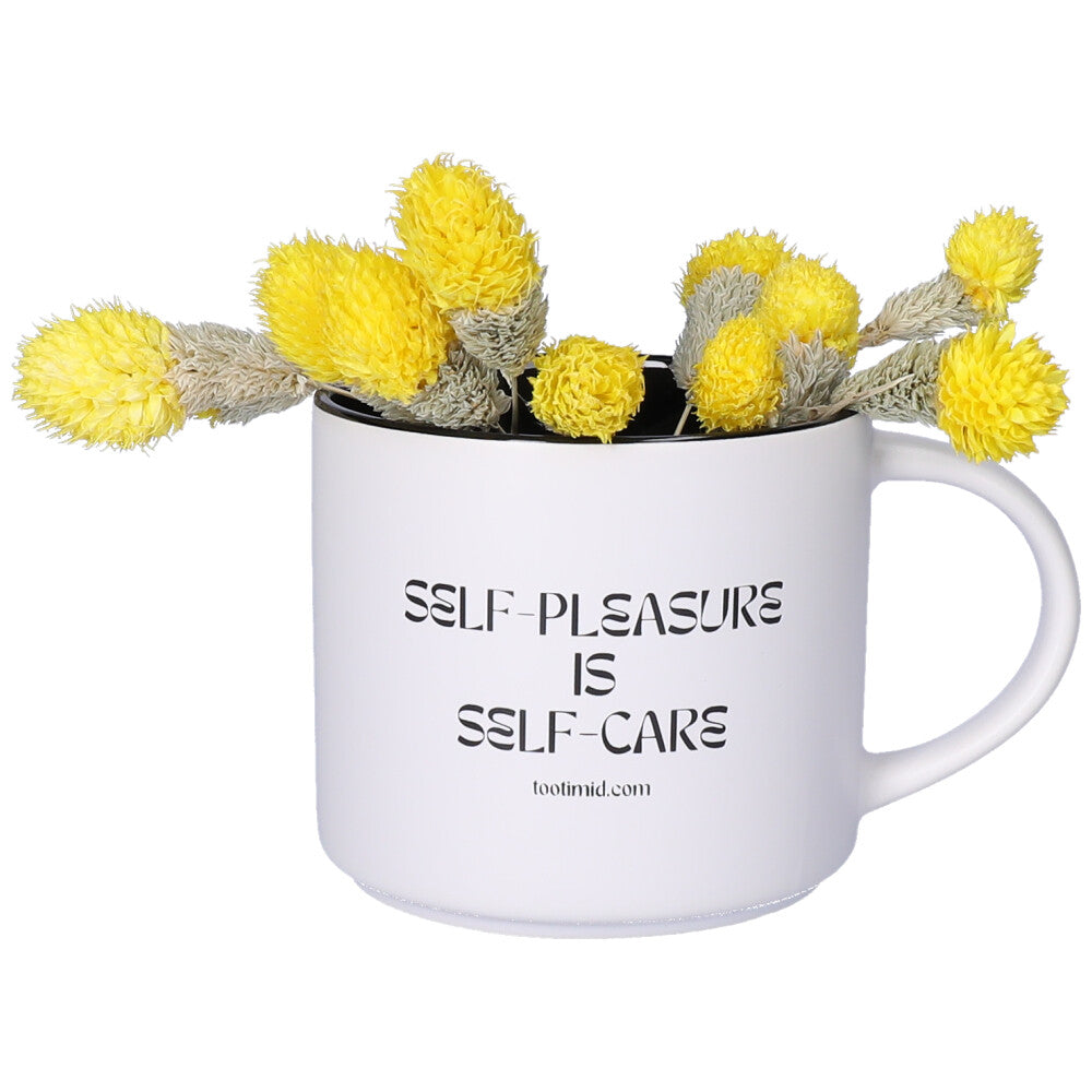 White Self-Pleasure is Self-Care Mug facing forward with yellow flowers in it