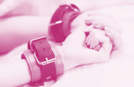 woman with french manicure wearing handcuffs in bed 