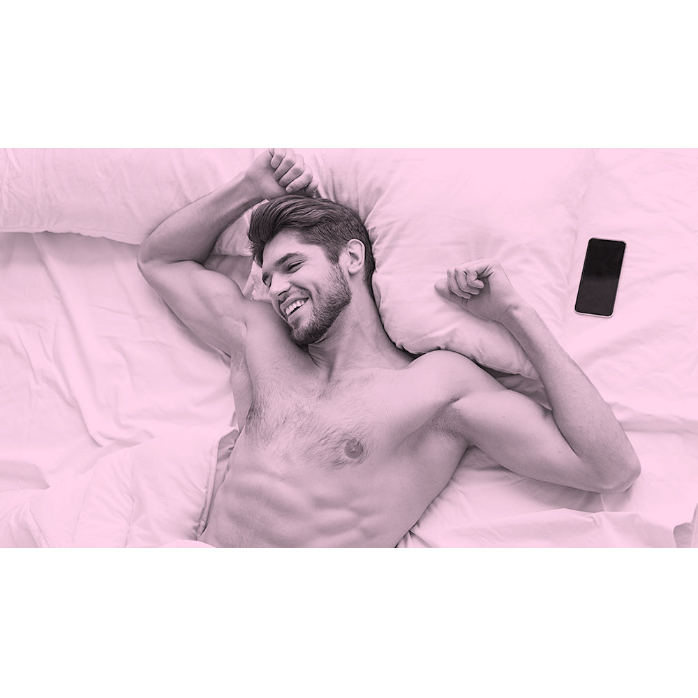 Man laying shirtless in bed with smile on his face