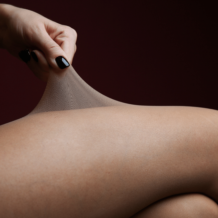 Image of a person's thigh wearing nylon pantyhose, with a hand pulling the sheer fabric away from the leg. Read our article of 13 surprising sexual fetishes and kinks you've never heard of.