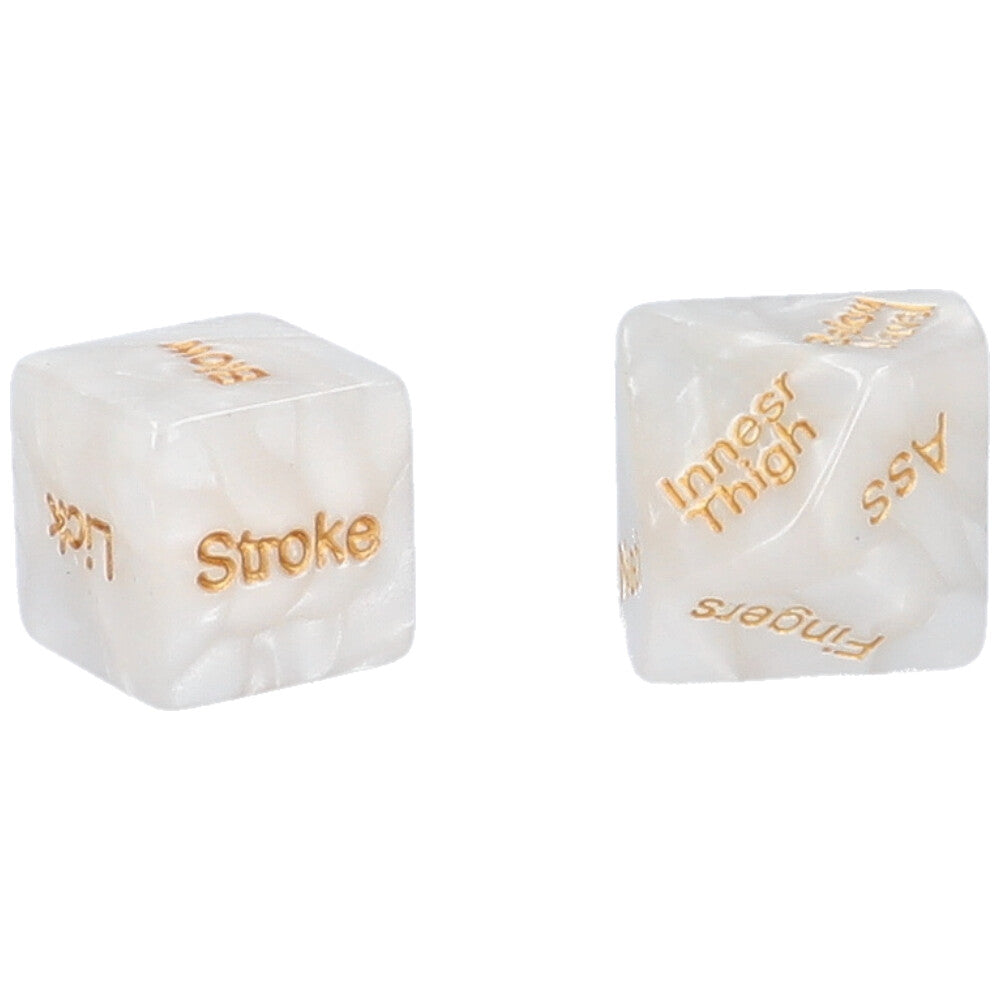 A pair of white & gold foreplay dice with body parts on one die and directions on the other. This image shows “stroke” and “lick” showing on one die and “ass”, “inner thigh”, and “fingers” showing on the other.