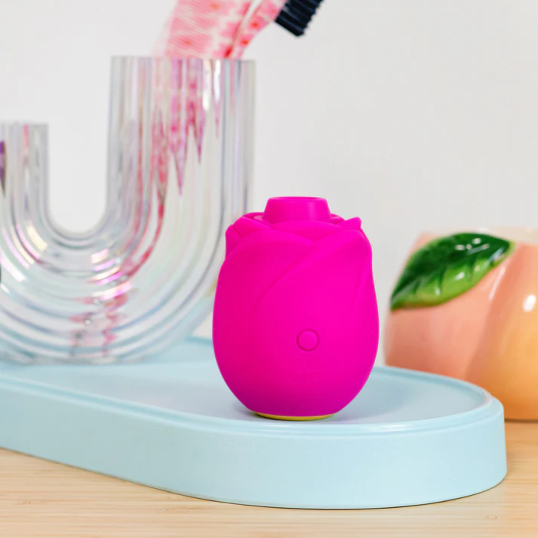 close up of Romp Rose 2.0 Rechargeable Silicone Air Clitoral Stimulator on bedside table 
