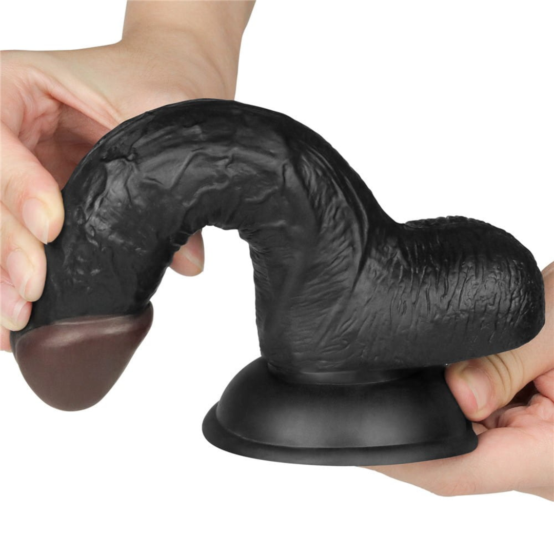 hands bending black dildo from Easy Strap on Set 7.0 inches to show flexibility 