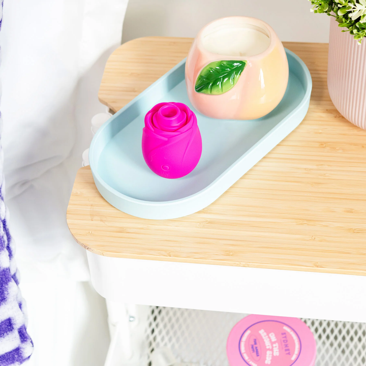 Romp Rose 2.0 Rechargeable Silicone Air Clitoral Stimulator as seen on bedside table 