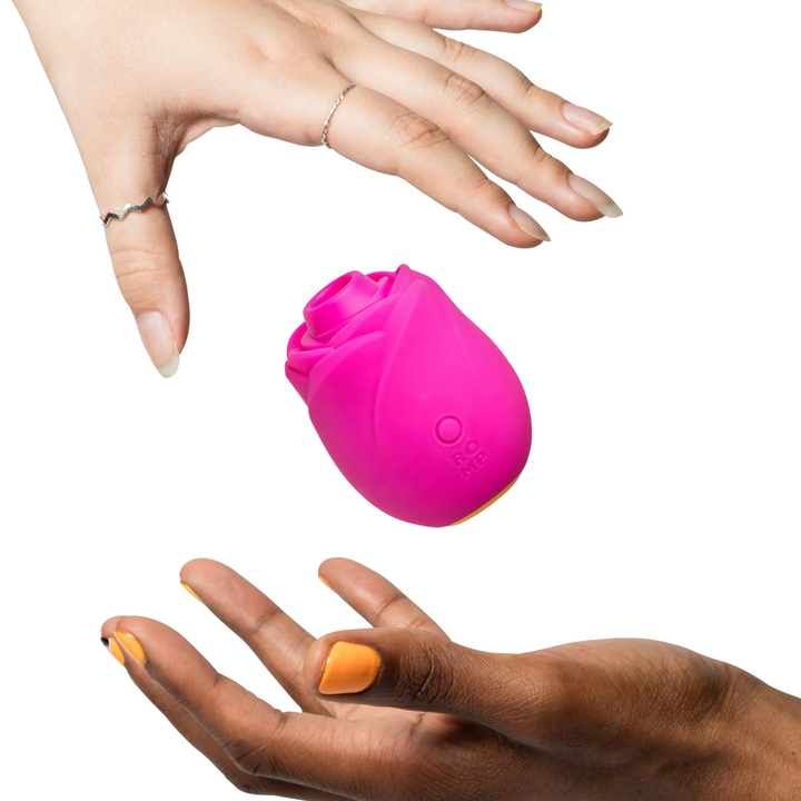 hands passing Romp Rose 2.0 Rechargeable Silicone Air Clitoral Stimulator back and forth 