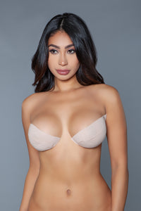 Beige breast adhesive on model resembles bra cups