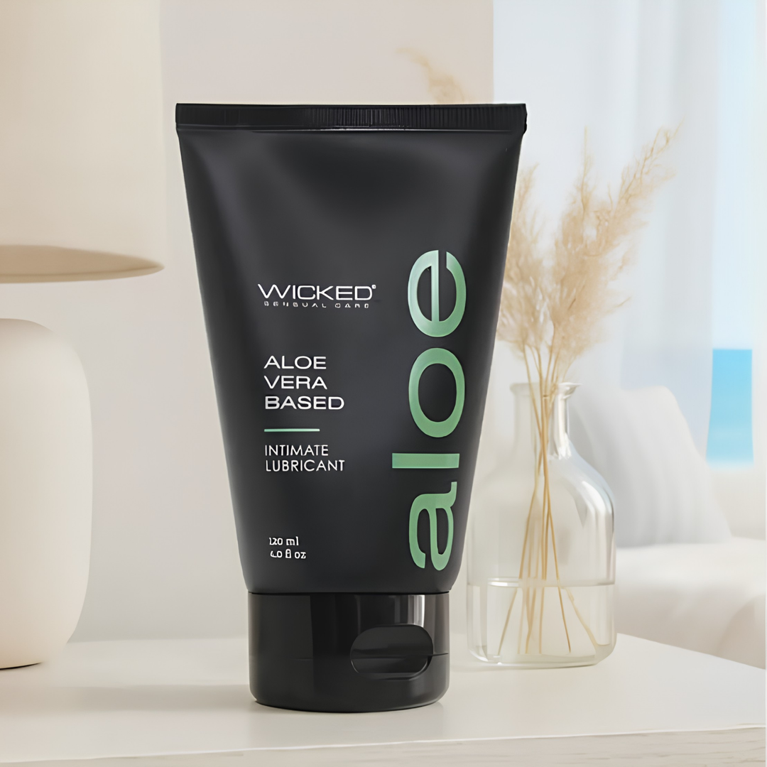 Wicked Sensual Aloe Lubricant 4oz with bedroom backdrop 