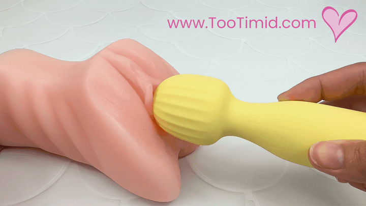 GIF of yellow mini wand vibrating on a model of a vagina