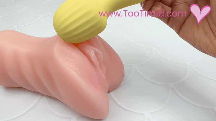 GIF of yellow mini wand vibrating on a model of a clitoris