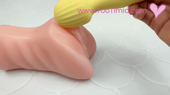 GIF: Sideview of yellow wand vibrating on a model of a clitoris