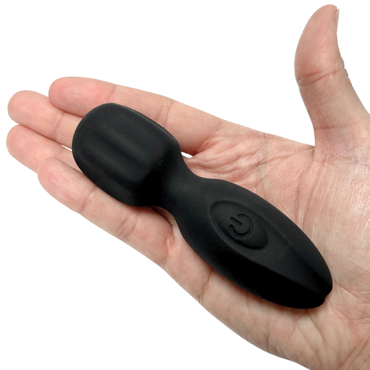 Black silicone mini wand held in palm of hand against a white background