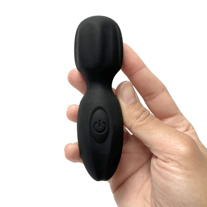 Black silicone mini wand held in a hand against a white background