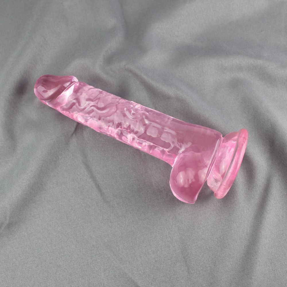 Realistic Suction Cup Dildo with Balls on it's side on top of a bed spread.