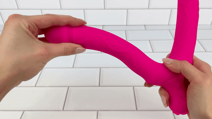 GIF of hot pink double penetration vibrator  one shaft being bent to show smooth veins flexibility 