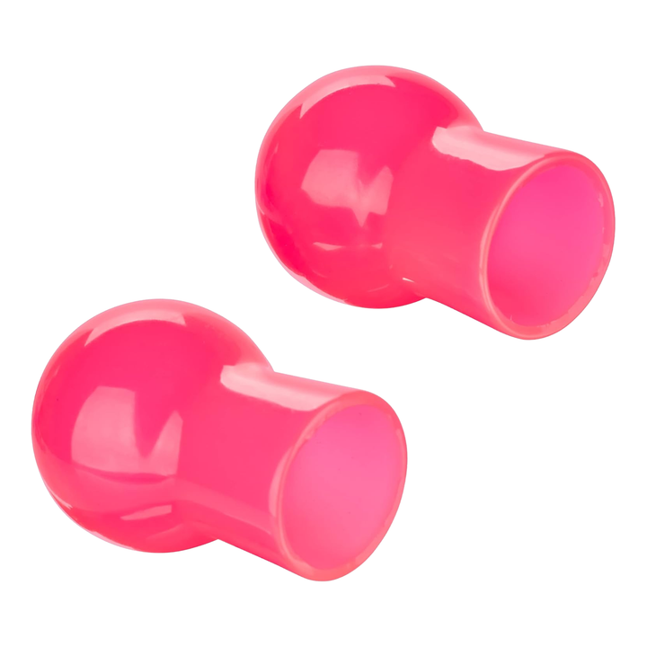 Two pink plastic nipple suckers on their side on a white background