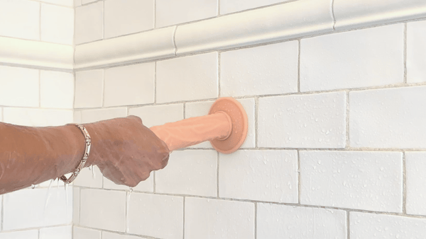 GIF of hand pulling suction cup dildo on shower wall 