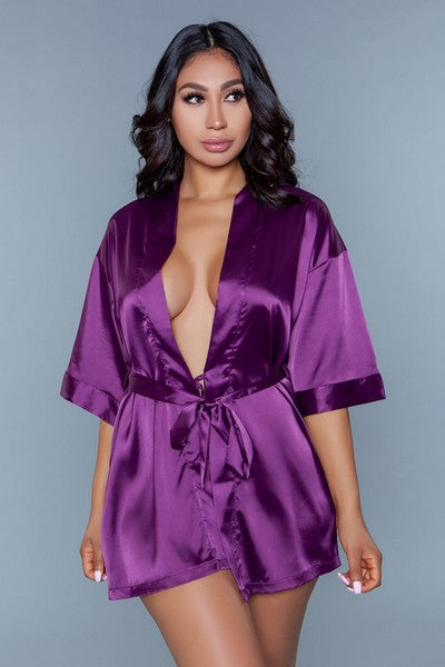 Model facing forward wearing purple satin robe with side pockets. 3/4 sleeves and satin sash front tie