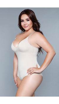 Model wearing seamless bodysuit body shaper with adjustable straps, and snap bottom closure in beige facing front left