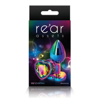 Image of the packaging for the Rainbow Heart Jeweled Metal Butt Plug in Rainbow color. Text reads rear assets, NS Novelties, aluminum.