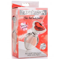 Image of the packaging for the Booty Sparks Red Heart Gem Glass Anal Plug. Text reads Booty Sparks, make that booty sparkle, warm up or cool down, sexy see-through glass, red heart gem glass large anal plug